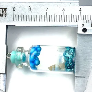 Vue macro mesurant le pendentif bouteille en verre de 3,7 cm avec coquillages et perles