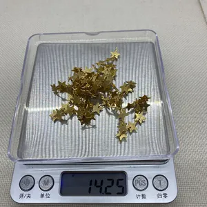Detailed shot of golden star jewelry charms on a digital scale weighing 14.25 grams