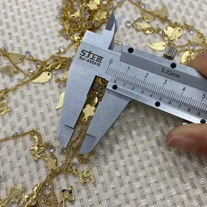 Detail view showing golden floral and musical note charms size measurement using calipers