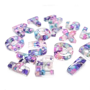 Close-up of resin alphabet beads with colorful stone inlay for DIY necklace jewelry