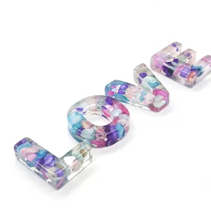 Macro shot of LOVE letter charms filled with colorful crushed resin stones for DIY jewelry