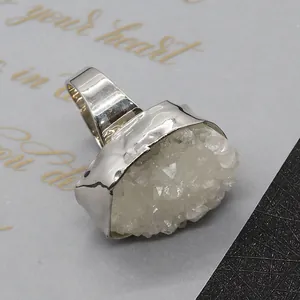 Macro view of a large silver irregular white crystal ring with hammered metal texture details