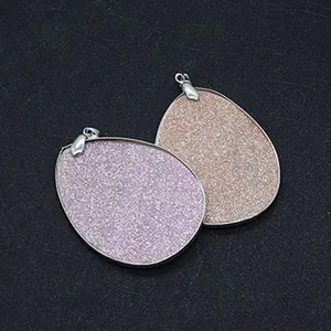 Detail of drop-shaped shell pendants with shimmering glitter finish and silver metal frame