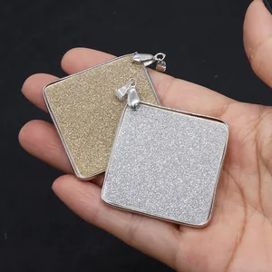 Détail macro de pendentifs carrés en nacre dorée et argentée avec texture pailletée
