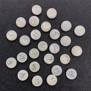 Macro shot of white shell alphabet beads with gold engraved letters for DIY jewelry making
