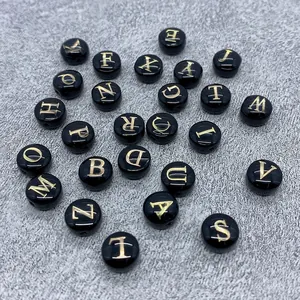 Close-up of 8mm round flat shell beads with gold letters A-Z for DIY jewelry making
