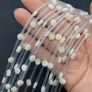 Detailed macro view of white daisy floral charms on transparent DIY jewelry craft beads