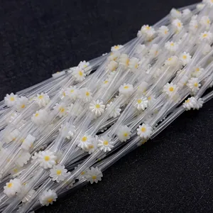 Macro detail of white shell daisy flower beads with yellow centers for DIY jewelry