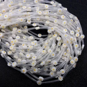 Macro detail of bundled daisy-shaped beads with white petals and yellow cores for DIY crafts
