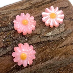 Dettaglio di perline a margherita rosa in resina per gioielli fai-da-te su corteccia naturale