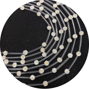 Transparent daisy flower straws with white petals and yellow cores on black background