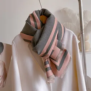 Detail of grey and pink cashmere-like scarf showing soft texture and fringe edges on coat
