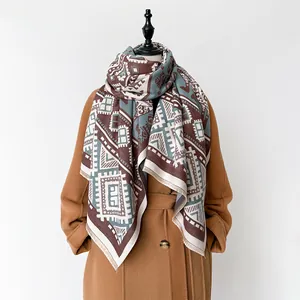 Ethno-Schal mit geometrischem Muster aus Kaschmir-Imitat über einem kamelfarbenen Mantel