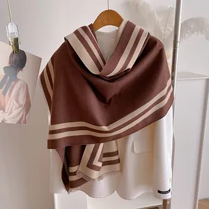 Close-up of thick winter scarf featuring geometric beige lines and delicate fringe trim