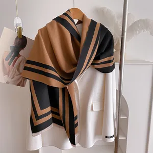 Detail of camel and black cashmere-feel scarf with geometric stripes and fringe edge