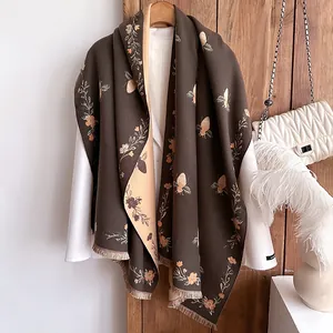 Close-up of jacquard bee and floral pattern with tassel edges on a thick cashmere-like scarf