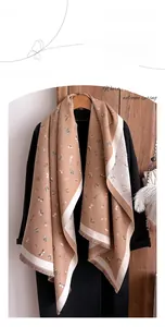 Detail of faux cashmere scarf with butterfly print and tassels on a black coat