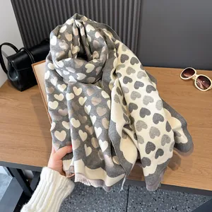 Detail showing the thick cashmere-like texture and fringed edges of the heart print scarf