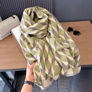Detail of soft thick cashmere-like scarf with green geometric cube pattern and fringed edges