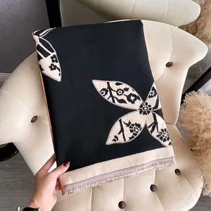 Close-up of black cashmere scarf with beige flower print and elegant fringe details