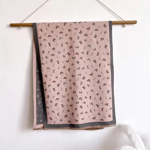 Detailed close-up of double-sided cashmere-feel scarf with delicate butterfly print and tassels