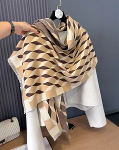 Detail of cashmere-like scarf with brown geometric diamond patterns and fringe trim