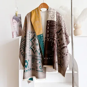 Detail of bohemian knit shawl with geometric patterns and tassel edges on a wooden hanger