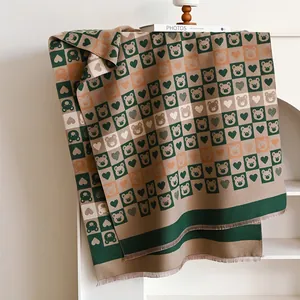 Détail d'écharpe d'automne à damier avec motifs ours et cœurs et bords frangés
