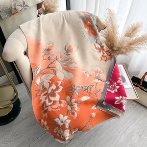 Detalle de bufanda jacquard cálida con motivos de magnolia naranja y flecos finos