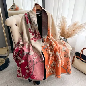 Elegante bufanda de jacquard con motivos de magnolia y flecos sobre un sofá beige
