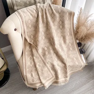Detailed texture of beige cashmere-style shawl with vintage floral pattern and soft tassels