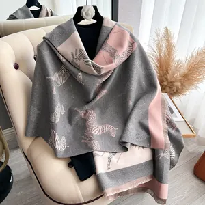 Detail of soft pink and grey zebra print scarf with fine fringe edges on a chair
