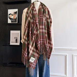Detail of checkered plaid scarf with fringes and Good Luck patch on a model