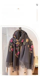 Detail of floral embroidery and fringe on dark grey faux cashmere scarf on a model