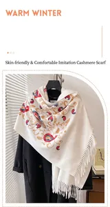 Dettaglio della sciarpa pashmina bianca con ricamo paisley e frange su un cappotto