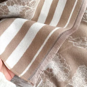 Detail eines weichen gestreiften Schals mit Damastmuster und Fransen in Beige