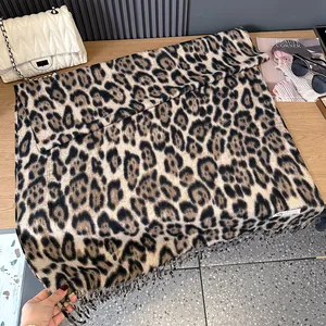 Close-up of leopard print scarf texture with fringe details and woven label on a table