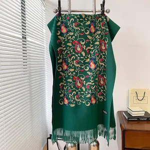 Dettaglio del ricamo paisley e nappe su scialle etnico verde scuro effetto cashmere