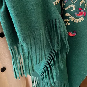Dettaglio scialle etnico verde scuro con ricamo paisley e lunghe frange decorative