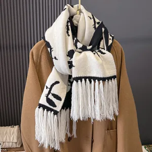 Classic black and white knit scarf with floral pattern and fringe on camel coat