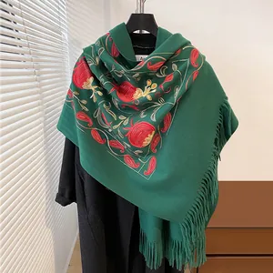 Détail d'une écharpe vert foncé style cachemire avec broderie florale et de longs franges