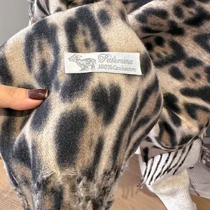 Detailed close-up of 100% cashmere leopard print scarf showing soft texture and fringe