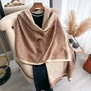 Macro view of geometric jacquard pattern and soft fringe on brown cashmere scarf