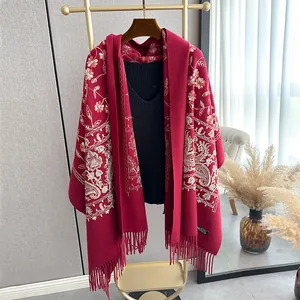 Detailed embroidery of floral and paisley patterns on a dark red tassel shawl wrap