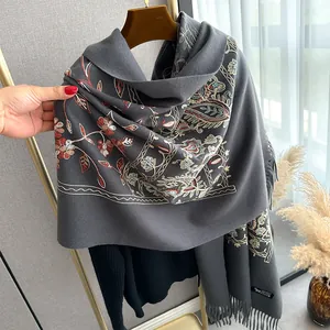 Close-up of floral embroidery and fringe detail on a thick grey cashmere winter shawl