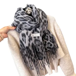 Elegant grey leopard print cashmere scarf with tassel edges on a beige knit sweater