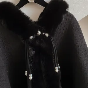 Detail of black knitted shawl with faux fur collar and elegant white pearl accents