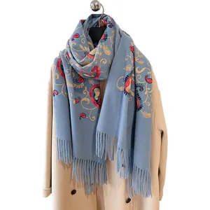 Sciarpa in cashmere azzurro con ricami paisley e nappe abbinata a un cappotto beige