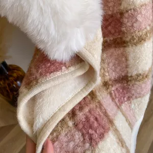 Detail eines rosa karierten Plüsch-Ponchos mit weißem Kunstfellbesatz und warmem Futter