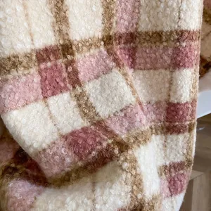Nahaufnahme von dickem Lammwollstoff mit Karomuster in Weiß, Rosa und Braun für den Winter